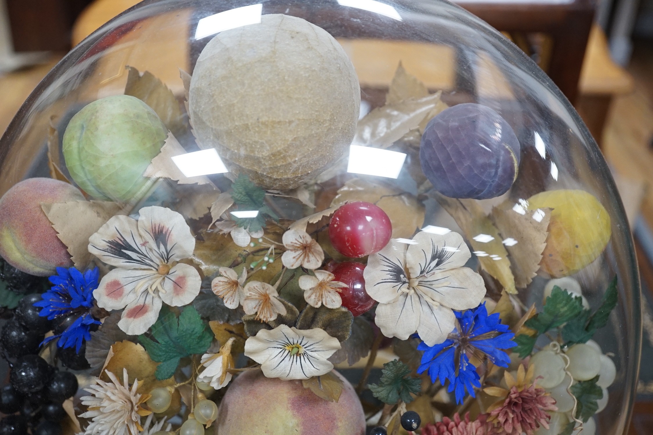 A Victorian painted mache fruit arrangement under a glass dome, 58cms high